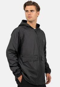 Zwarte lichtgewicht jas met capuchon, gesloten met een rits aan de voorkant, twee grote opgestikte zakken, elastische manchetten en een gladde, waterafstotende textuur.