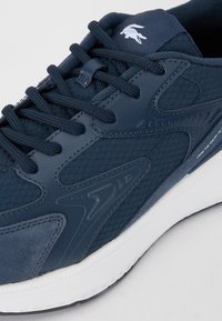 Granatowe sneakersy z teksturowanej tkaniny z gładkimi akcentami, w tonacji sznurowadła oraz białą podeszwą. Firanowany logo na języku.