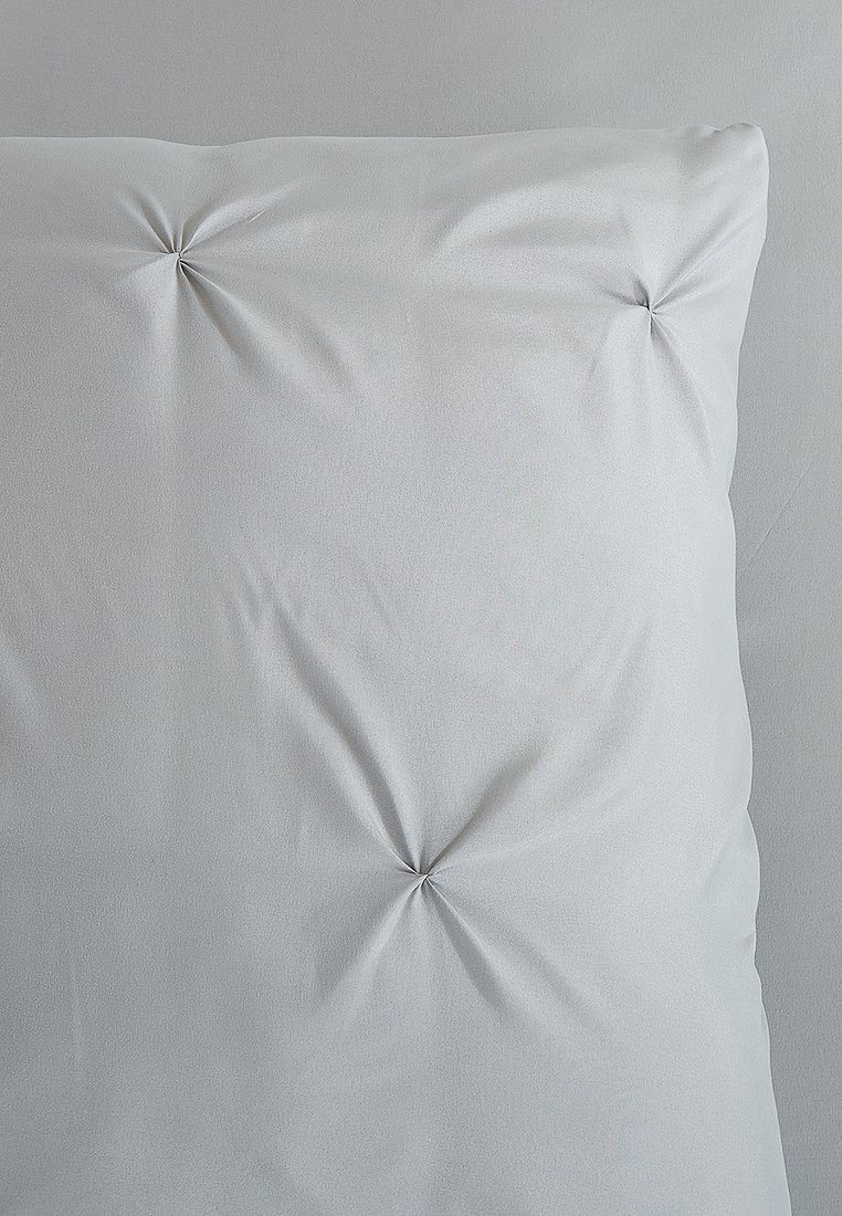 Coussin gris avec une texture de tissu lisse et quatre boutons centrals capitonnés, présentant une forme rectangulaire simple et un design minimaliste.