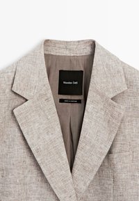 Beige hørblazer-krave med Massimo Dutti mærke og "Made in Portugal" tag inde i jakkens for.