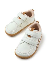 Baskets synthétiques blanches avec des bandes Velcro, accents beiges, collier rembourré et semelle en caoutchouc. Bout rond et détails de surface texturés.