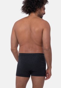 Boxer shorts a righe nere con una morbida texture del tessuto. Presentano un elastico comodo e un design aderente, visti da dietro.