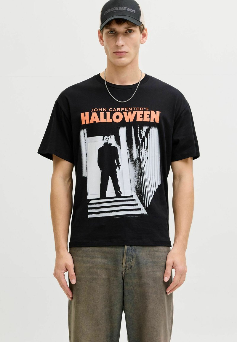 Crna pamučna majica s grafičkim otiskom figure iz "Halloween" s narančastim tekstom. Uparena s izblijedjelim sivim trapericama.