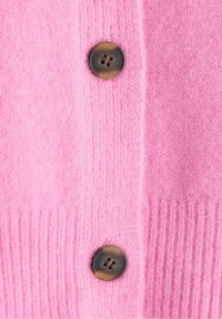 Rosa yllekofta med ribbat avslut och två mörkbruna knappar med fyra hål var. Mjuk textur med en slät yta.