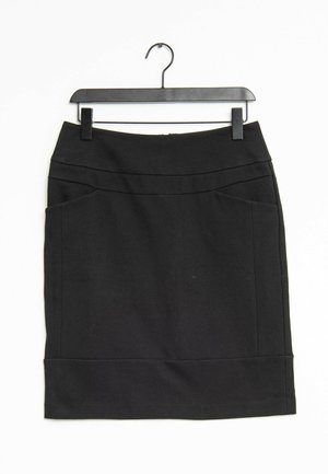 Jupe crayon noire longueur genou avec poches latérales, suspendue sur un cintre en plastique noir sur fond blanc.
