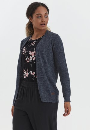 Cardigan lavorato a maglia blu navy con apertura frontale, maniche lunghe e finitura testurizzata. Abbinato a un top con stampa floreale nera e pantaloni neri.
