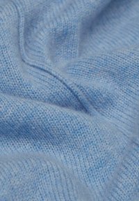 Hellblauer gestrickter Stoff mit einer weichen, strukturierten Oberfläche, die feine Muster und ein leicht verschwommenes Aussehen aufweist.