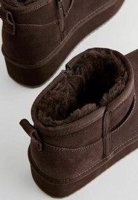 Bottines en suede brun avec doublure en fourrure, dotées d'une fermeture éclair, d'une languette au talon et d'une semelle robuste pour le confort et la durabilité.