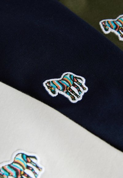Bomuldsbeklædning i marineblå, creme og olivengrøn med et farverigt, stribet broderet hestelogo på hvert stof. Glat tekstur og rene kanter.