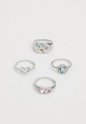 Quatre bagues : une bague en argent massif avec des pierres précieuses colorées, une bague en forme de cœur, une bague avec une pierre ronde aux accents bleus, et une bague en cabochon rose en forme ovale.