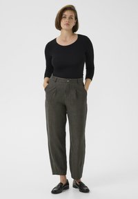 Black long-sleeve top paired with gray textured high-waisted trousers featuring front pleats and side pockets, complemented by black loafers.