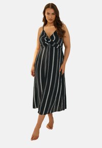 Svartvit randig maxiklänning med knuten frontdetalj, som har tunna axelband och en flödande kjol. Slät tygtextur.