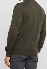 Dunkelgrüner Strickpullover mit glatter Textur, langen Ärmeln und ribbeltem Saum. Verfügt über ein klassisches Kragen-Design.