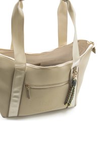 Borsa shopping beige in materiale sintetico, con chiusura a zip, tasca esterna e nappine decorative. Texture liscia e forma strutturata.