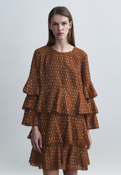 Robe brune à étages avec manches longues à volants, présentant un motif à pois et un col arrondi. Tissu léger avec une finition texturée.