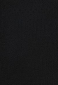 Černá pletená textilie s texturovaným vzorem zahrnujícím kruhové a vertikální prvky, což vytváří jemný pocit hloubky a vrstvení.