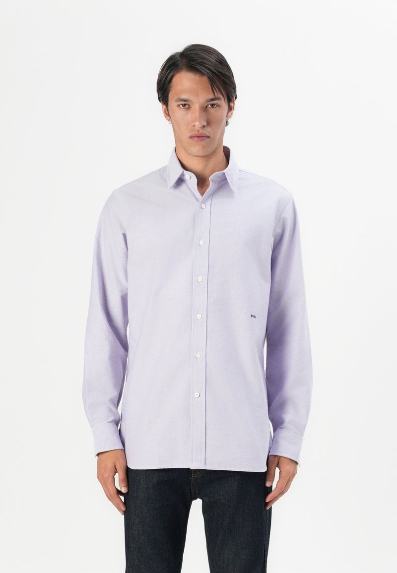 Camisa de manga larga lila con cuello de botones, presenta una tapeta frontal, botones blancos y un sutil detalle de logo en el pecho.