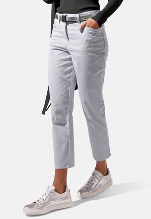 Gestreifte Baumwollhose mit tailliertem Bund, vorderen Taschen und verkürzter Länge, kombiniert mit metallischen Sneakers.
