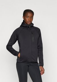 Mustavärinen vetoketjullinen takki, jossa on korkeakauluksinen malli, raglan-hihat, sivutaskut ja tyylikäs viimeistely. Sileä rakenne, kevyt suunnittelu.