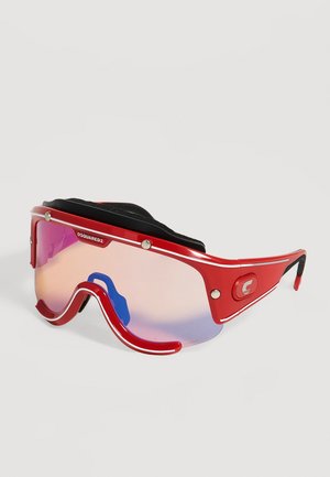 Lunettes de soleil de sport rouges avec des verres enveloppants teintés rose, des plaquettes de nez noires et une bride rembourrée noire sur le dessus.
