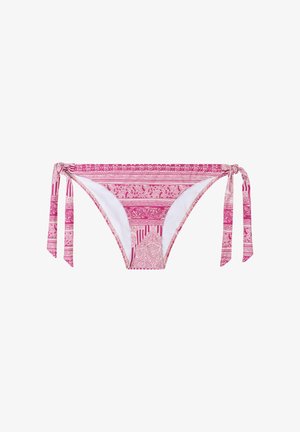Frau lächelt mit geschlossenen Augen, trägt einen rosa Bikini mit Muster und seitlichen Bindungen, steht vor einem Hintergrund aus Holzpaneelen.