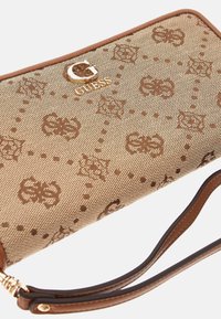 Portafoglio marrone con motivo, dotato di una superficie in tessuto testurizzato, con un logo dorato "G" e un braccialetto in pelle marrone. Dettaglio della chiusura con zip visibile.