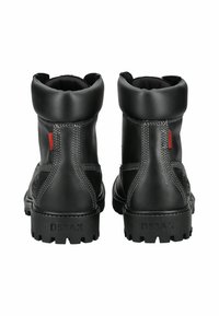 Botas de cuero negro con un acabado liso, parte superior redondeada, costuras visibles y suelas de goma resistentes con un dibujo en el relieve.