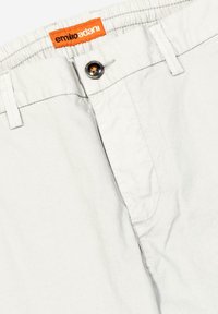 Hellgraue Baumwollshorts mit elastischem Bund, einem Knopfverschluss und einem orangefarbenen Markenlabel oben. Mit weißen Nähten.