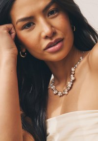 Gold-toned necklace featuring alternating round pearls and crystals, highlighting a mix of smooth and faceted textures.