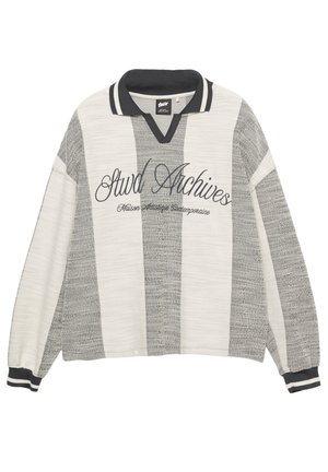Sivi i bijeli prugasti džemper s V-izrezom, rebrastim crnim ovratnikom i manšetama. "Stwd Archives" izvezena crnim pismom na prednjem dijelu.