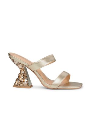 Sandale glissante en métal doré avec deux brides, équipée d'un talon triangulaire orné de gemmes claires et dorées. Texture lisse, design à bout ouvert.