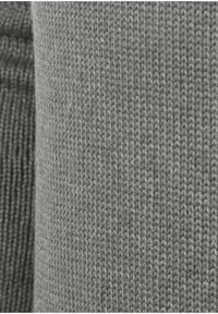 Grijze gebreide stof met een zachte textuur, met duidelijke steekpatronen. Twee tinten grijs naast elkaar gepresenteerd, die hun subtiele verschillen benadrukken.