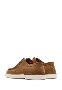 Chaussures en suedine marron avec bout arrondi, à lacets, et semelle en caoutchouc blanche ; présentent de subtils détails de couture sur le talon.