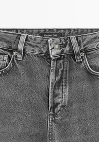 Zwarte denim jeans met een klassieke vijf-pocketontwerp, voorzien van een knoopsluiting, riemlussen en een label op de tailleband.