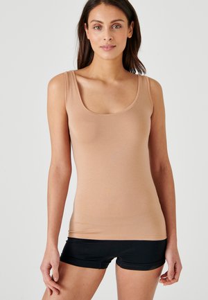 Top senza maniche beige realizzato in tessuto morbido, caratterizzato da un collo a giro e una vestibilità slim, abbinato a pantaloni corti neri.