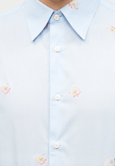 Ανοιχτό γαλάζιο πουκάμισο με κουμπιά και φαρδύ γιακά με μικρά, διάσπαρτα λευκά και ροζ λουλούδια.