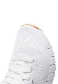 Chaussure de sport blanche avec un dessus en mesh respirant et une semelle rembourrée. Comprend des lacets plats, une semelle intermédiaire légèrement texturée et une semelle extérieure en caoutchouc antidérapante.