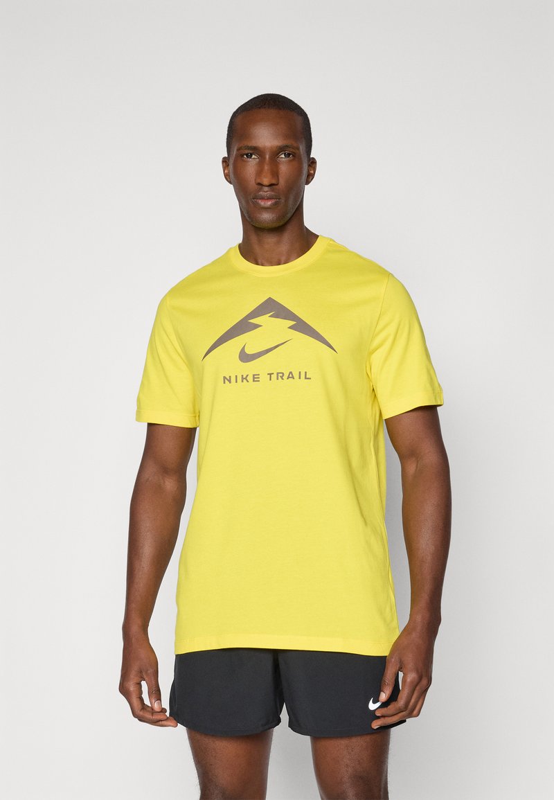 Kollane puuvillane T-särk lühikeste varrukatega, tumesinise Nike logo ja "NIKE TRAIL" tekstiga, sile tekstuur, tavaline lõige.