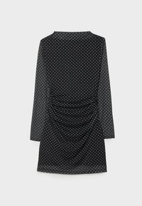 Schwarzes Kleid mit langen Ärmeln, das mit weißen Polka-Dots versehen ist, Raffung an der Taille und einem glatten, leichten Stoff. 