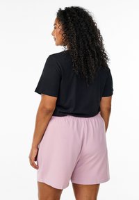 Czarny t-shirt z krótkim rękawem o luźnym kroju w połączeniu z szortami w jasnoróżowym kolorze z elastycznym pasem, o gładkiej fakturze.
