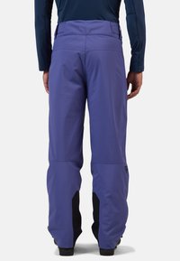 Paarse waterdichte broeken met een gladde textuur, versterkte zwarte accenten bij de enkels en een brede tailleband voor comfort.
