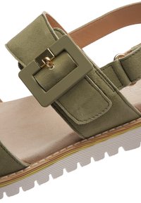 Zelená semišová sandála s širokým remienkom, veľkou obdĺžnikovou nastaviteľnou prackou a bielou textúrovanou podrážkou so žltým akcentným pruhom.