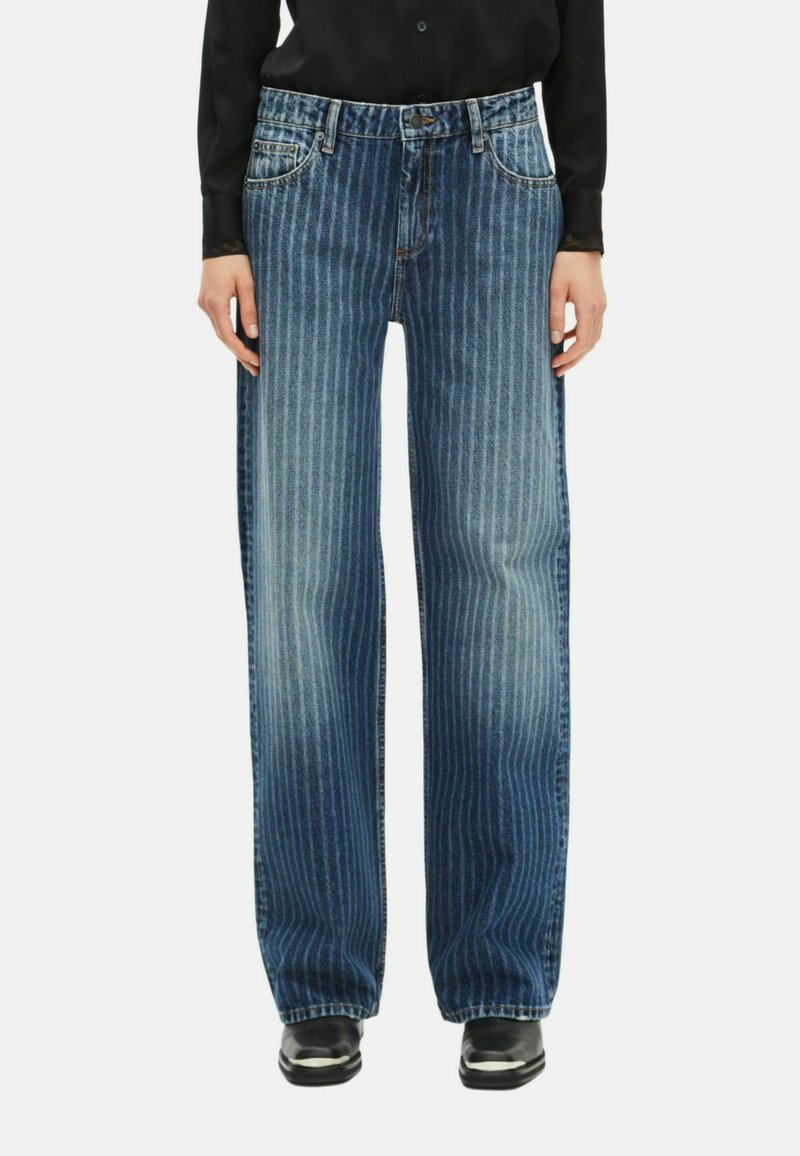 Niebieskie dżinsy z poziomymi paskami, luźny krój, pięć kieszeni, kontrastowe szwy i zapięcie na guziki w pasie.