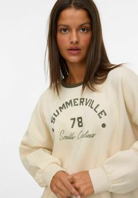 Sweatshirt de couleur cr�ème avec un col vert, affichant "SUMMERVILLE 78 Caroline du Sud" imprimé en lettres majuscules. Tissu doux, coupe décontractée.