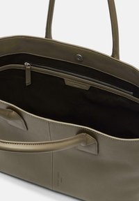 Zielona oliwkowa skórzana torba na ramię o gładkiej fakturze, szerokim otwarciu i wewnętrznej kieszeni na zamek. Zawiera dwie mocne uchwyty oraz subtelne detale przeszycia.