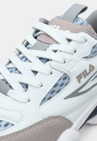 Αθλητικά παπούτσια σε ανοιχτό μπλε και λευκό χρώμα με γκρι λεπτομέρειες, διαθέτουν πλέγμα ανώτερου μέρους, υφή στη λαστιχένια σόλα και εμφανές λογότυπο στο πλάι.