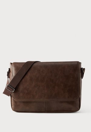 Sac messager marron en cuir synthétique avec bandoulière réglable en tissu marron foncé et fermeture à rabat sur fond uni.