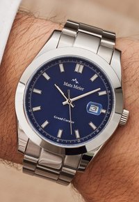 Montre en acier inoxydable argenté avec un cadran bleu, des index blancs, une fenêtre de date et un bracelet en métal brossé. Marque : Mats Meier, modèle : Grand Corner.