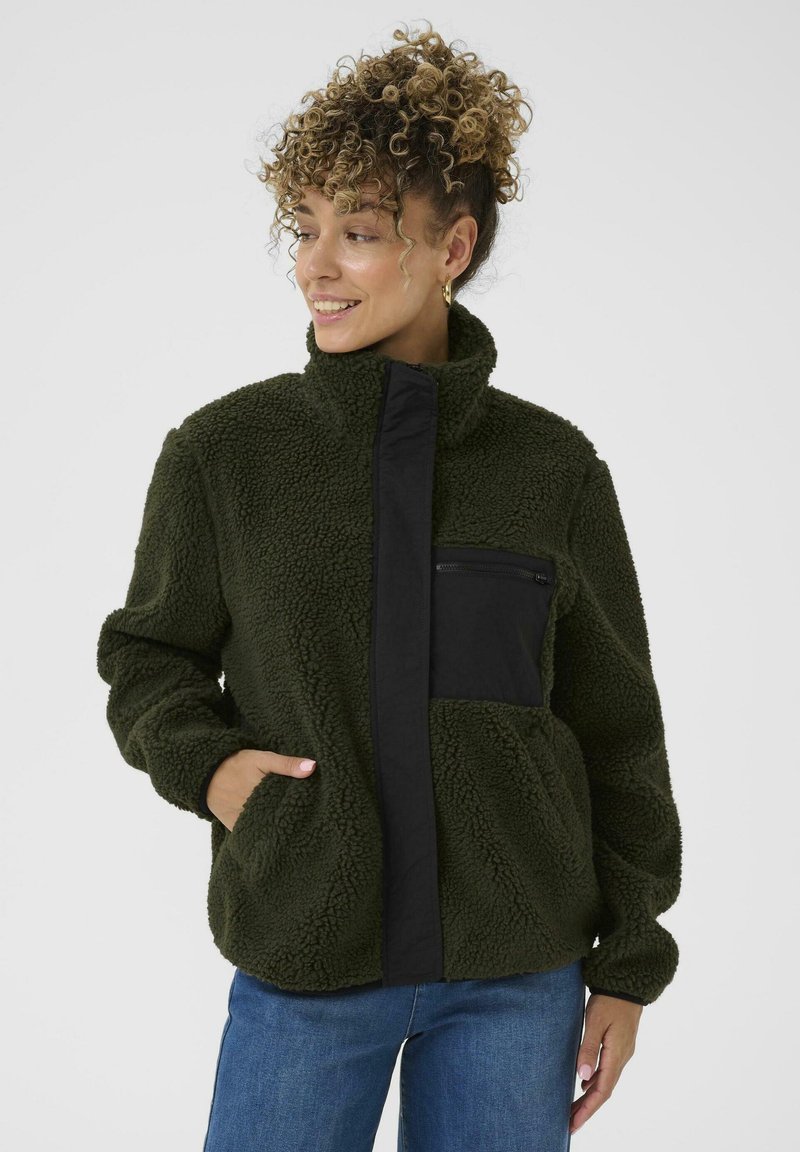 Groene fleece jas met hoge kraag, zwarte ritssluiting en twee zijzakken. Zachte textuur en ontspannen pasvorm. Lange mouwen met manchetten.
