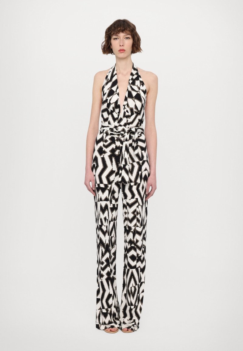 Zwart-wit halter jumpsuit met een diepe halslijn, voorzien van een geometrisch patroon, ceintuur in de taille en wijde broekspijpen. Gladde stofstructuur.